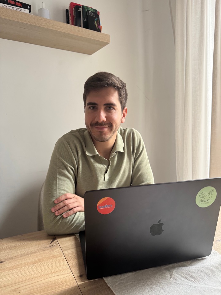 David sentado en su mesa con un portátil, en un entorno de trabajo cálido y sereno.